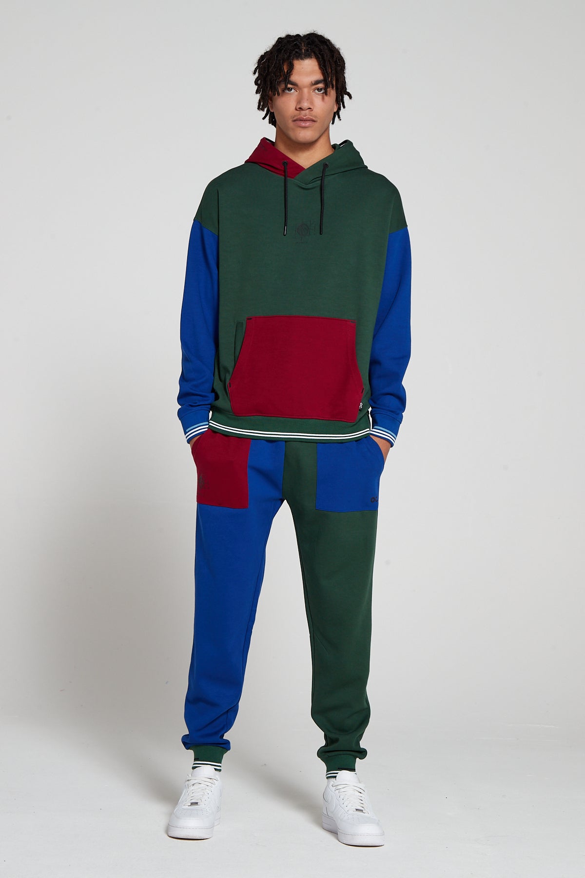 Full look of a model wearing oversized Original Creator Classic Hoodie in Multicolor pattern. This clothing features kangaroo poch and a zip pocket in hoodie. Model is also showing off complete Track set with classic multicolor Joggers and hands in the pockets of joggers