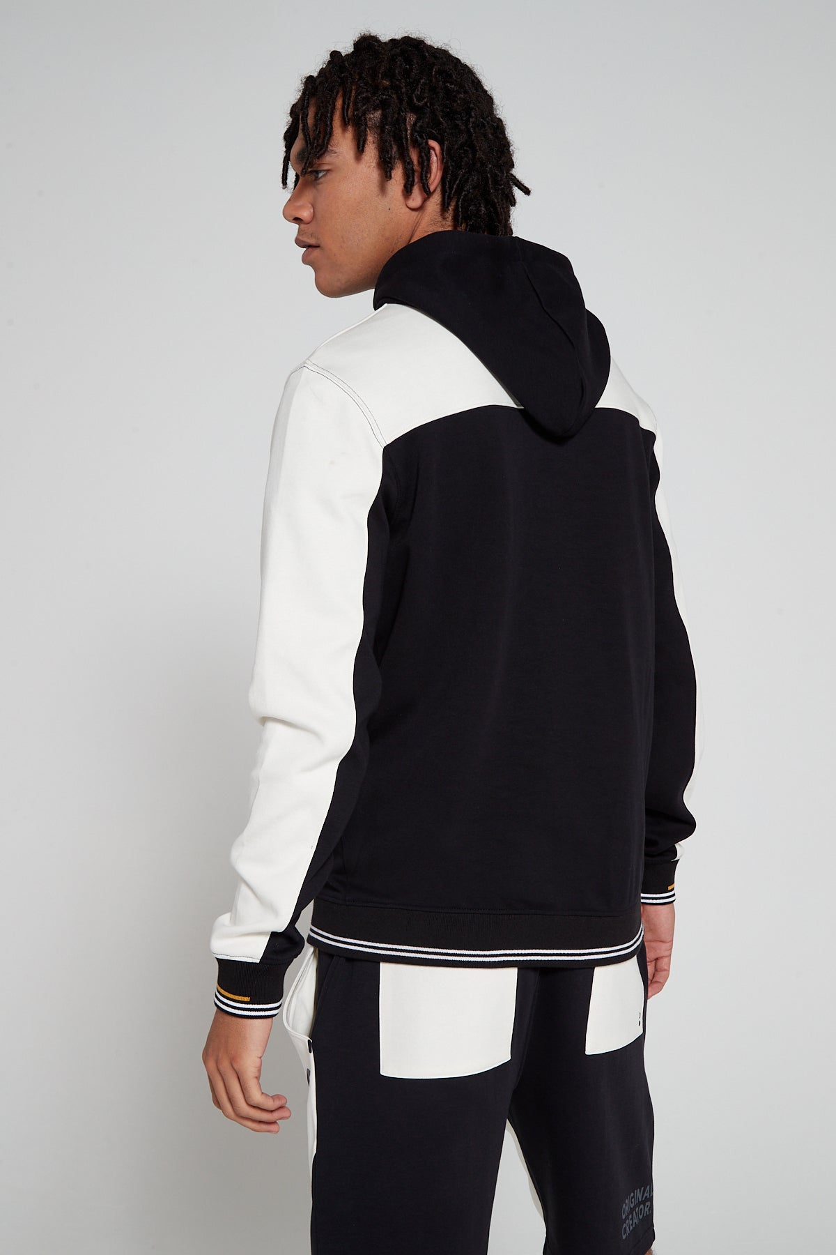 Model showing behind view wearing Original Creator Retro Zip Hoodie in Jet black color with no branding at the back and featuring water repellent technology and classic line pattern on the sleeves and color combination of white and black