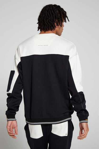 Model showing behind view wearing oversized Original Creator Retro Zip pocket Sweatshirt in Jet Black color with minimal branding at the back and color combination of black and off white on sweatshirt. Showing off the complete set with Off white and black retro joggers.