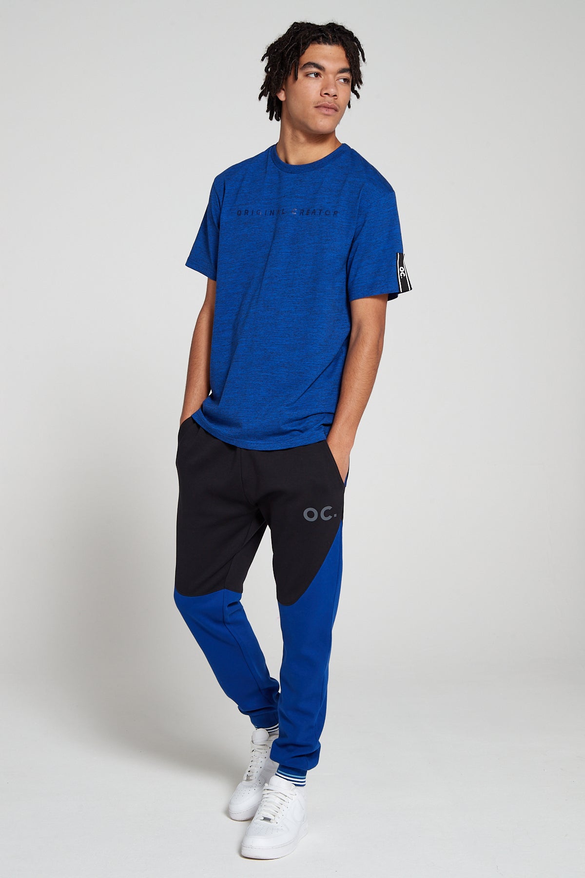 Full look of a model wearing Original Creator oversized Olympic Blue T shirt with minimum branding and features water repellent technology and wearing Original creator Olympic blue retro joggers 