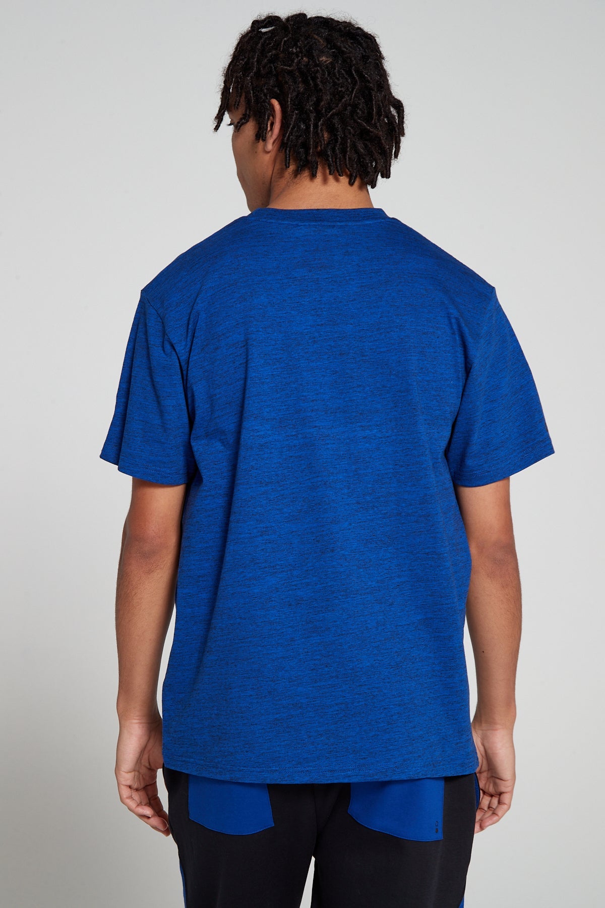 Model showing behind view wearing Original Creator oversized Olympic Blue T shirt with minimum branding at the back and features water repellent technology