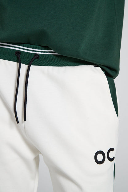 A close up shot of Original Creator Retro Joggers in Varsity green color and minimal branding on left thigh.