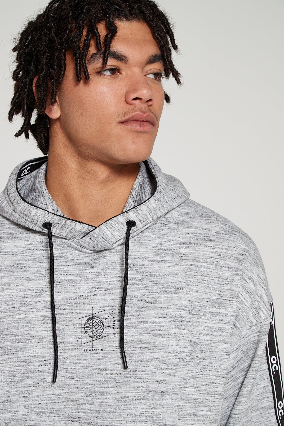 Model looking away showing front view wearing oversized Original Creator Classic Hoodie in Granite Grey color with globe print on center chest. 