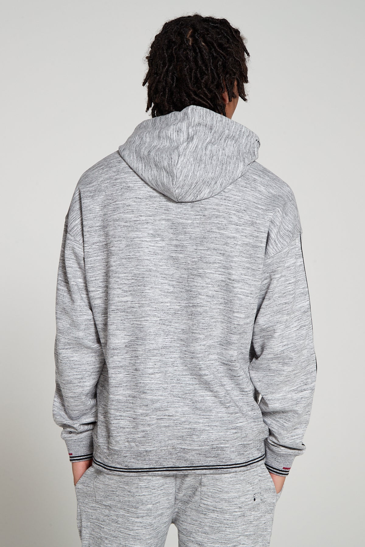 Model showing behind view wearing Original Creator oversized Classic Hoodie in Granite Grey color with no branding at the back and featuring water repellent technology and classic line pattern on the sleeves