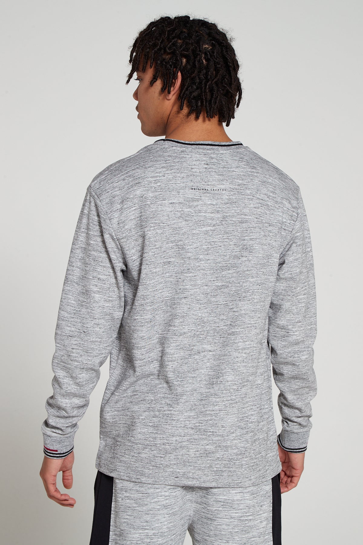 Model showing behind view wearing Original Creator Zip Pocket Long Sleeve Granite Grey T shirt with Minimalist branding at the back and features water repellent technology