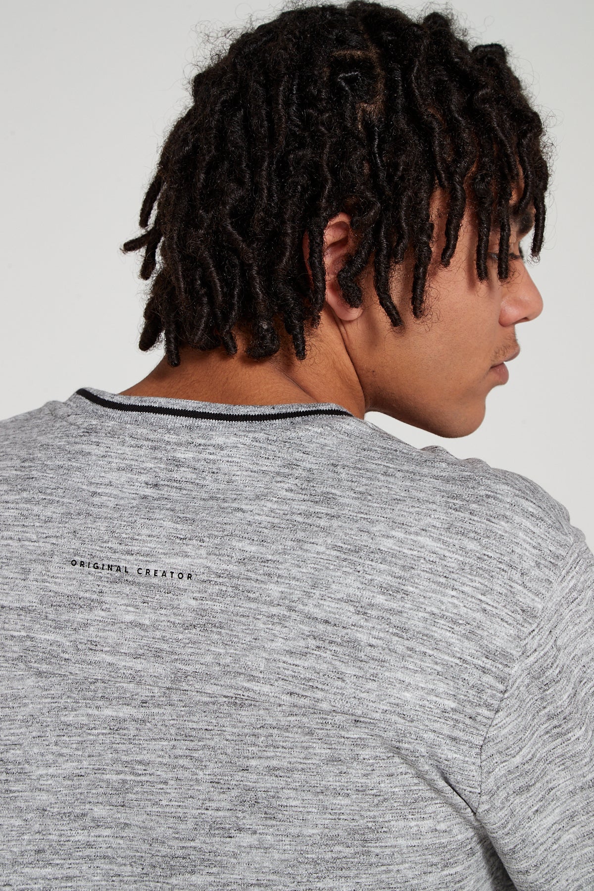 Model looking away showing behind view wearing Original Creator Zip Pocket Long Sleeve Granite Grey T shirt with Minimalist branding at the back