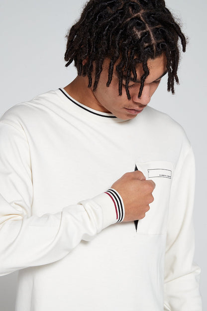 Model looking down opening zip pocket in a close up view wearing Original Creator oversized Off white Long Sleeve T shirt with very no branding and features water repellent technology zip pocket and round neck