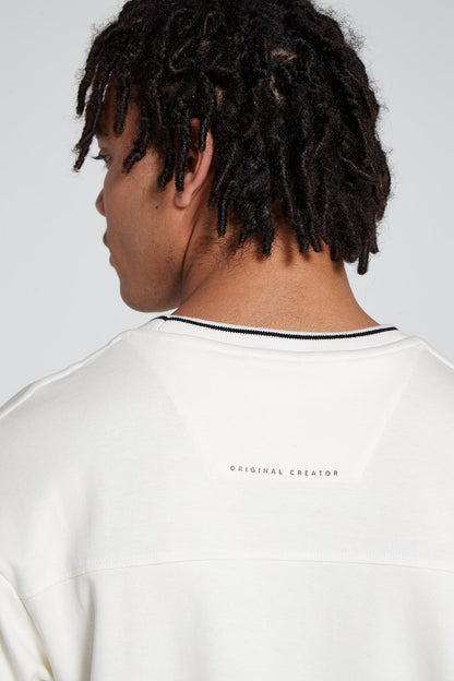 Model showing off Minimalist branding of Original creator Zip Pocket Long Sleeve Off white T shirt looking away in a close up from behind