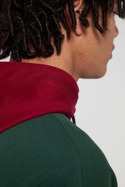 Model looking away showing side view wearing oversized Original Creator Classic Hoodie in Multicolor pattern with minimal branding on the hood.